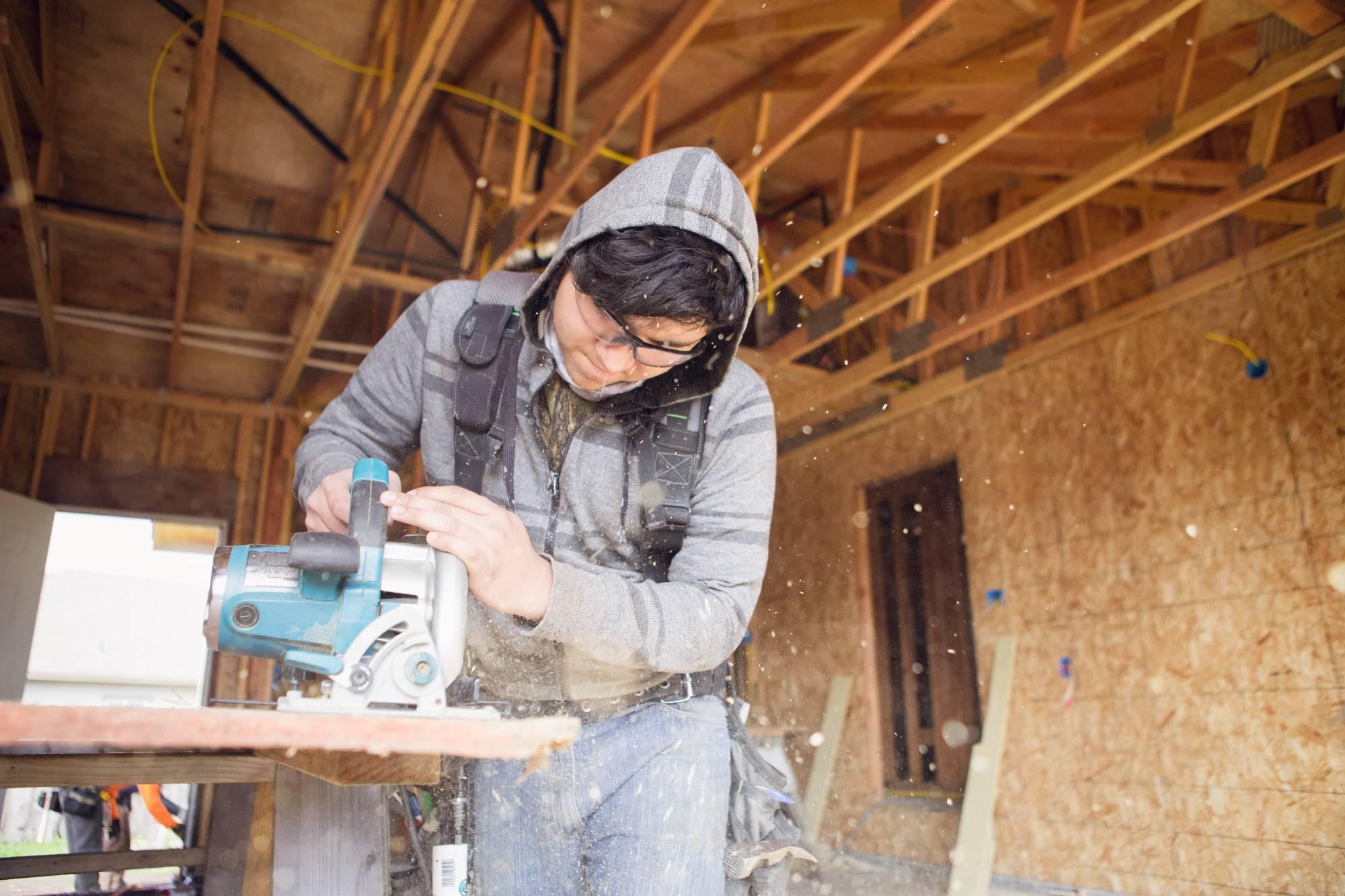 Student cutting plywood in a building site